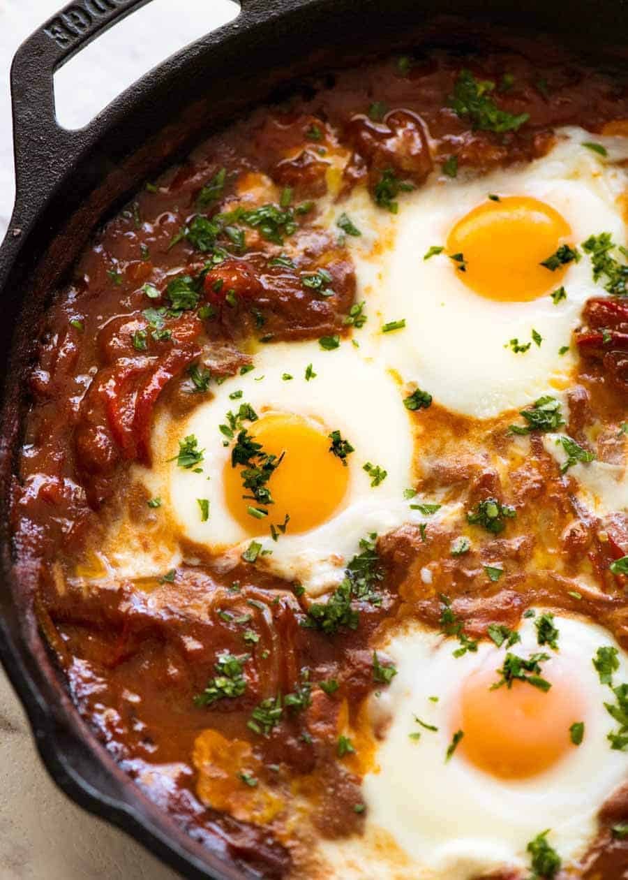 Close up of Shakshuka Middle Eastern baked eggs in a black skillet, fresh off the stove