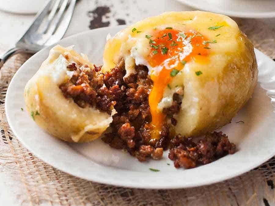 Close up of sausage spilling out of Sausage Egg Stuffed Potatoes on a plate, ready to be eaten
