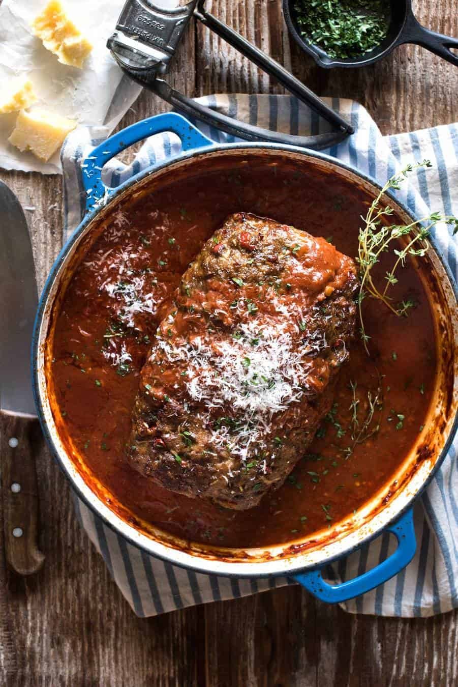 Italian Meatloaf with tomato marinara sauce in a round blue casserole pan with the end sliced off, revealing the juicy inside.