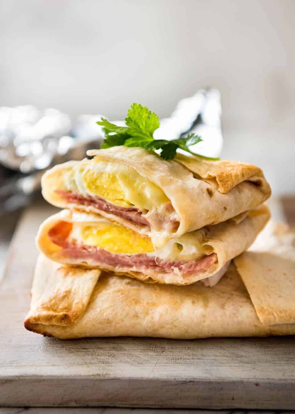 Stack of hot Ham, Egg and Cheese Pockets made with tortillas cut to show the inside with molten cheese and perfectly cooked egg.