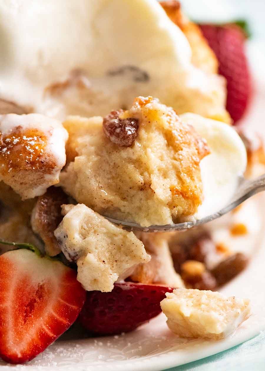 Close up of spoon with scoop of Bread and Butter Pudding with ice cream, showing how custardy the inside is