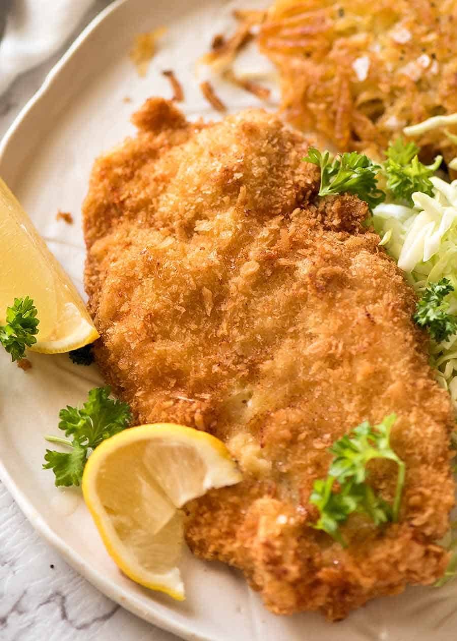 Overhead photo of crispy Schnitzel with lemon wedges