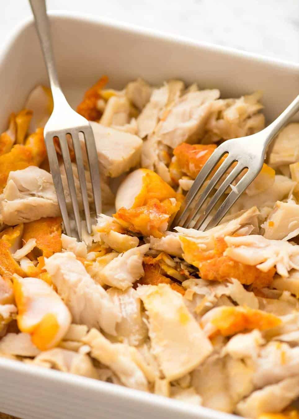 Flaking fish in white baking dish for Fish Pie