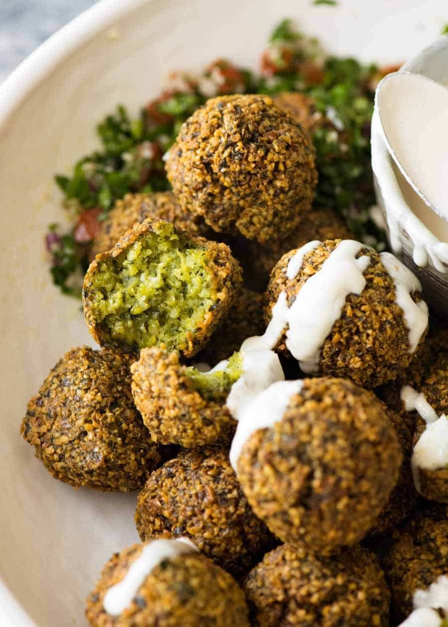 Close up of Falafels in a bowl drizzled with tahini sauce