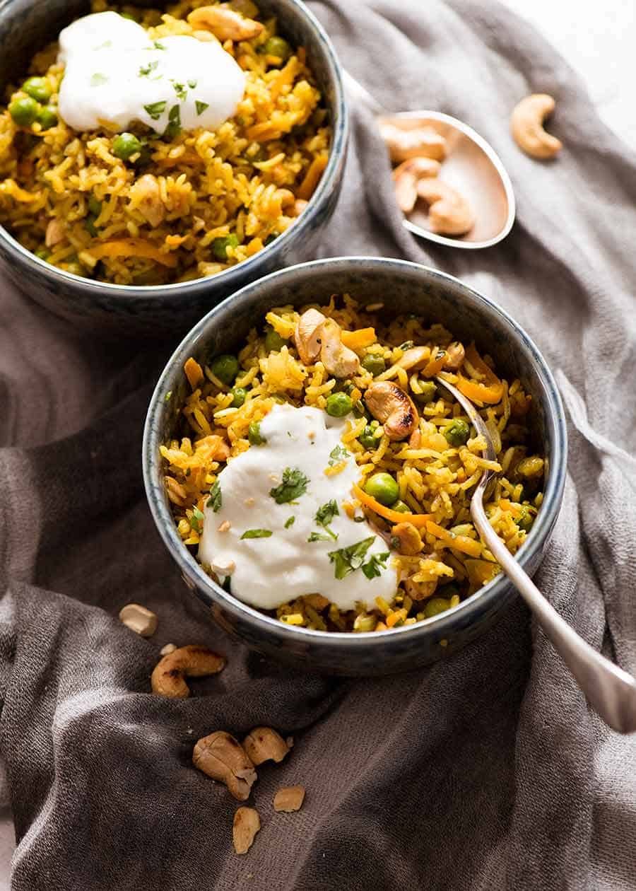 Two rustic bowls with Curried Rice made with Basmati Rice, topped with a dollop of yogurt