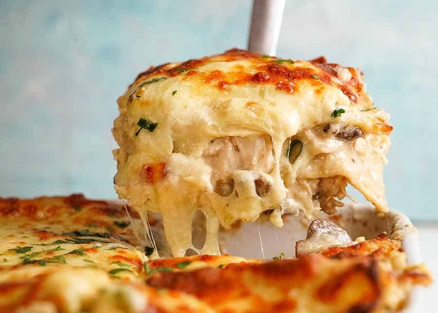 Spatula lifting up cheesy White Chicken Lasagna from baking dish