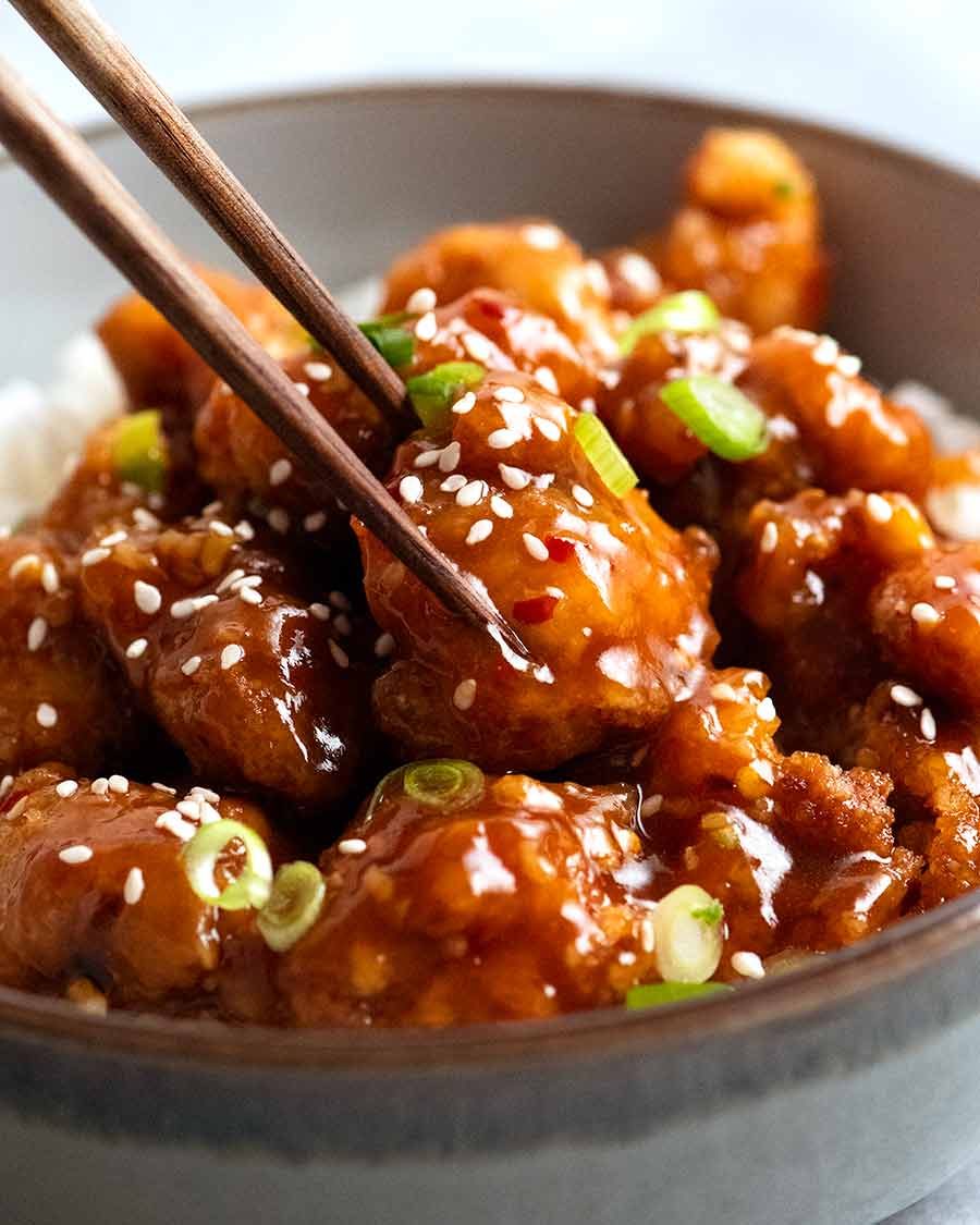 Close up of chopsticks picking up a piece of General Tso's Chicken