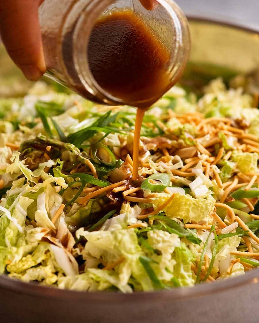 Pouring dressing over Chang's Crispy Noodle Salad