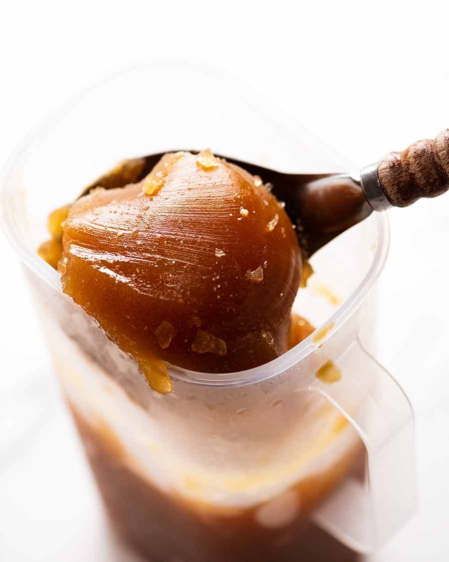 Cold beef stock being scooped up out of a jug