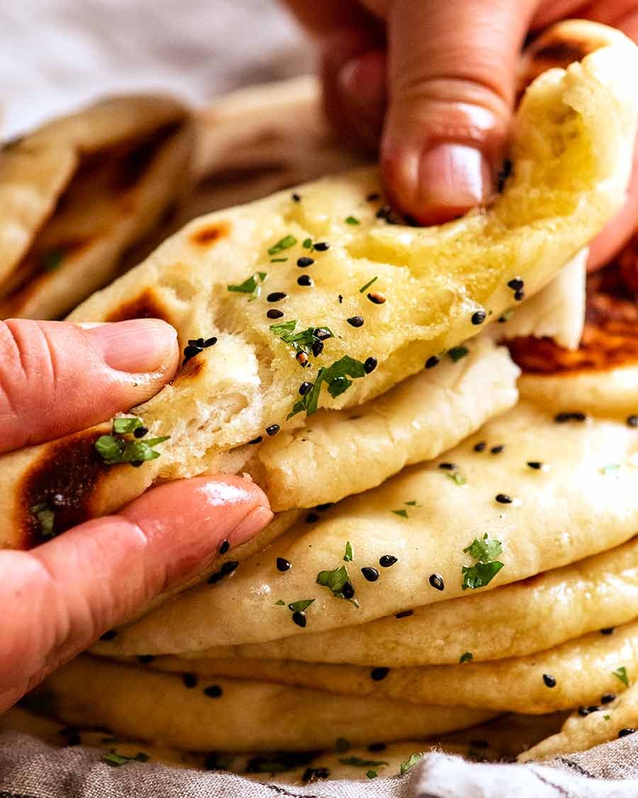 Tearing homemade naan to show how chewy it is