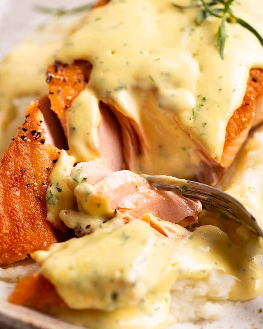 Close up of fork cutting into salmon with Bearnaise Sauce
