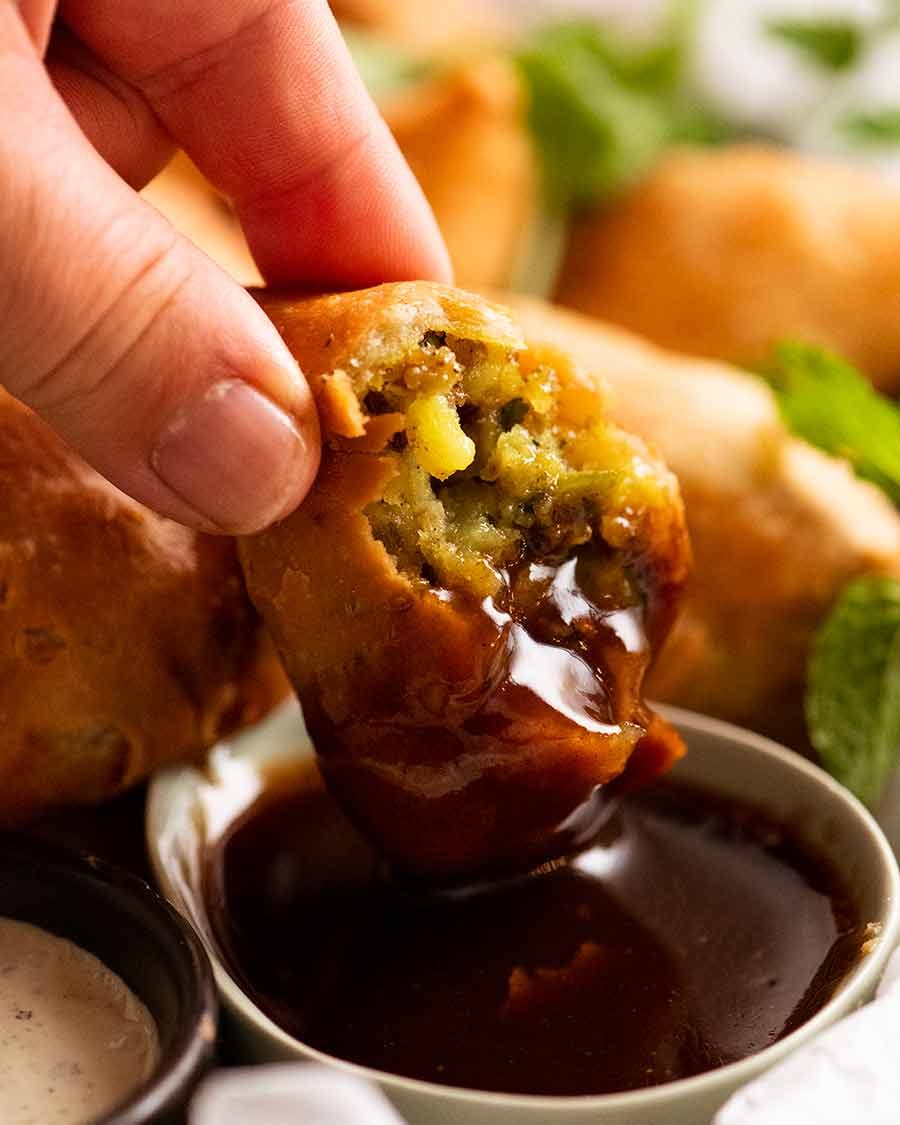 Dipping Samosa into tamarind sauce