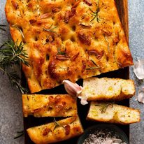 Overhead photo of Rosemary Garlic Focaccia on a wooden board, ready to be served