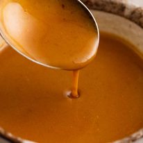 Close up of spoon drizzling Vermouth Jus