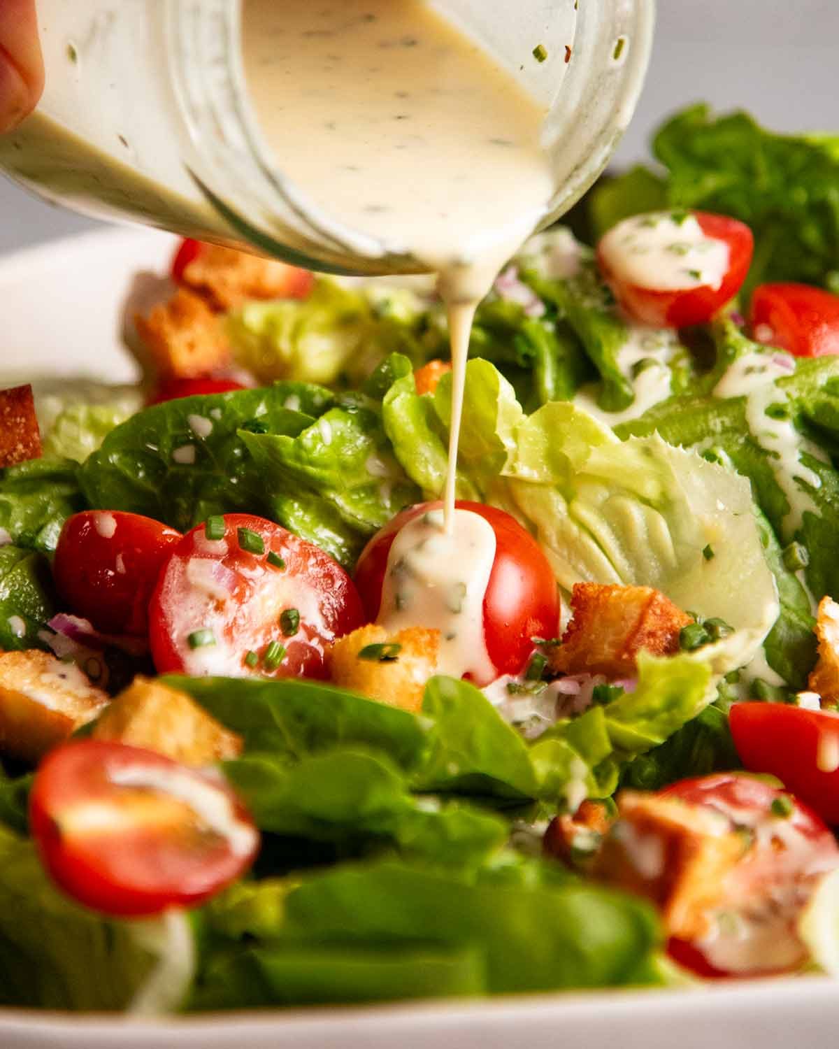 Pouring Creamy French Dressing over Baby Gem Lettuce Salad